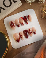 Crimson Petals press-on nails with deep red tips, nude base and elegant gold flower linework
