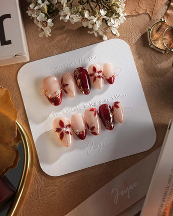 Crimson Petals press-on nails with nude base, crimson tips and hand-painted gold florals