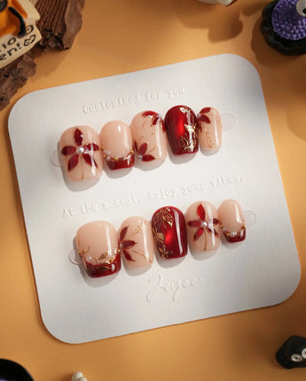 Crimson Petals press-on nails with deep red floral French tips and gold outline details