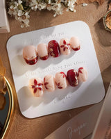 Crimson Petals press-on nails with glossy red French tips and gold floral nail art
