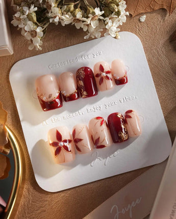 Crimson Petals press-on nails with deep crimson tips and delicate gold flower details
