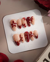 Crimson Petals press-on nails with glossy crimson French tips and delicate gold floral details