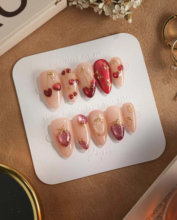 Crystal Berry press-on nails with red cherry cat-eye details, gold trim and glossy nude base