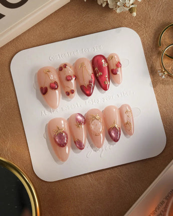 Crystal Berry press-on nails with glossy red cat-eye cherries and gold outlined nude nails