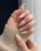 Spiral Twist press-on nails with pearly nude silk texture and delicate daisy accents
