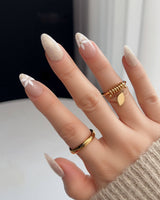 Close-up of Spiral Twist nails with pearly nude finish, silk texture, and daisy details
