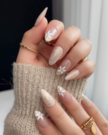 Spiral Twist press-ons with soft nude shimmer, daisy accents, and glossy gel surface