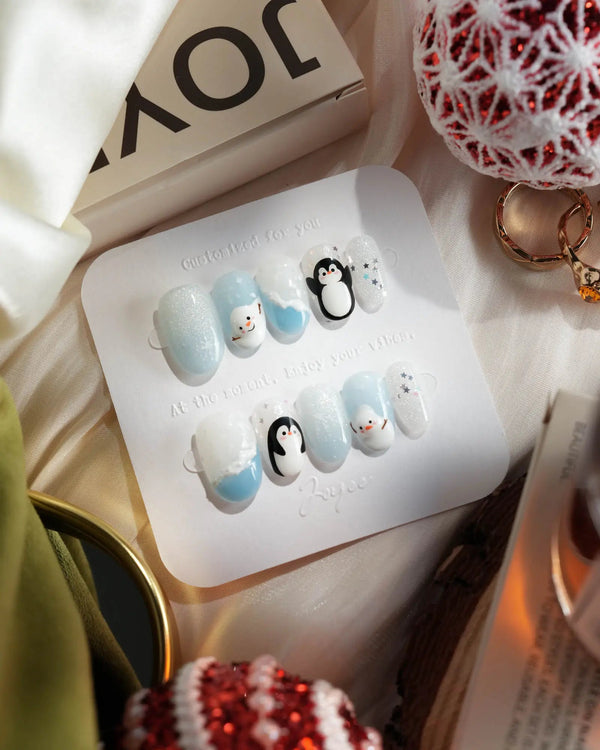 Cute icy blue and white winter nails with hand-painted penguins