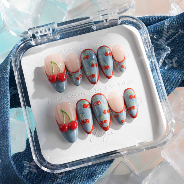 Denim Cherry medium almond nails with denim-textured tips, red French outlines, and cherry prints