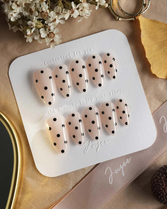 Dot Noir press-on nails with nude base, black polka dots and retro contrast styling