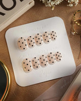 Dot Noir press-on nails with chic black polka dots on a nude glossy base