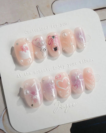 Dreamglow glossy pink press-ons with 3D bows, pearls, and gentle storybook styling