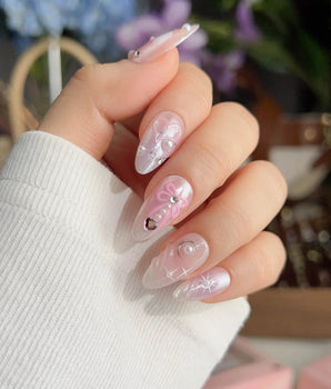 Dreamglow fairytale nails with soft pink shimmer, sculpted bows, and delicate pearls