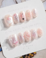 Dreamglow close-up of pearl pink nails with tiny bow sculpture and magical softness