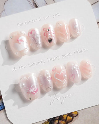 Dreamglow close-up of pearl pink nails with tiny bow sculpture and magical softness