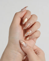 Dreamland Glow press-on nails with gold butterfly reliefs, glossy nude base and fall shimmer