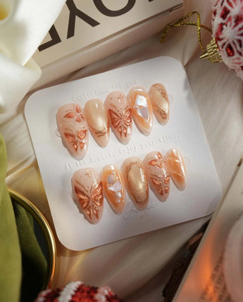 Dreamland Glow press-on nails with 3D gold butterfly accents and soft glossy shimmer