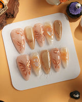 Dreamland Glow press-on nails with sculpted gold butterflies, nude base and glossy finish