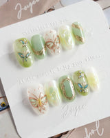 Dreamland sage green cat-eye nails with chrome vines and glowing butterfly art