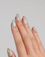 Pastel Relic nails with pastel milky base, metallic gold line art, and soft celestial details