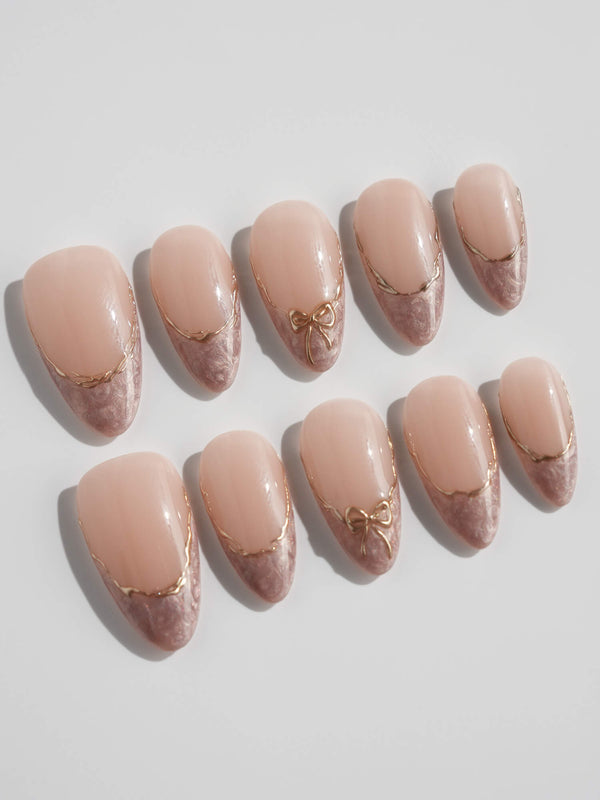 Nude almond-shaped nails with pearl French tips and metallic gold lines