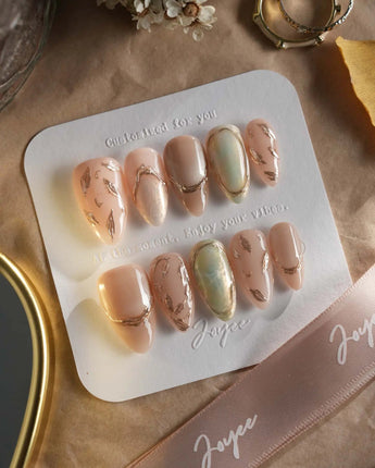 Earthy glow press-on nails with soft neutral fall tones, gold foil and leafy details