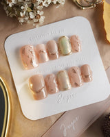 Earthy glow press-on nails with soft peach nude gel, gold foil and autumn leaf accents