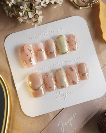 Earthy glow press-on nails with soft peach nude gel, gold foil and autumn leaf accents