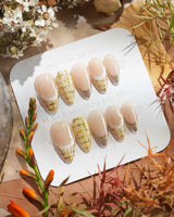 Tweed Light press-ons with glossy nude base, golden tips, plaid texture, and dainty lace art