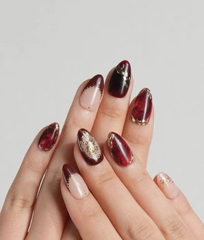 Gilded Merlot press-on nails with burgundy cat-eye shimmer and gold rose accents