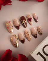 Close-up of Gothic Red press-on nails with 3D metallic crosses and ornate burgundy details