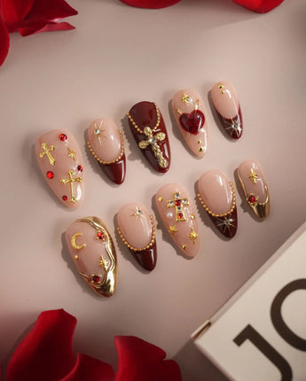 Close-up of Gothic Red press-on nails with 3D metallic crosses and ornate burgundy details