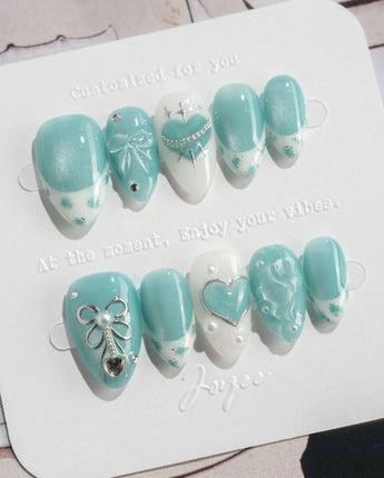 Exuma Blue extra short almond nails with light blue shine, heart accents, and ripples