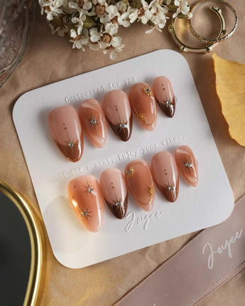 Fall Makeup nails with glossy brown gradient, 3D gold stars, and delicate gem placement