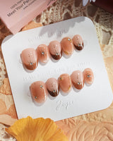 Fall Makeup nail close-up with glossy brown gradient and dimensional gold star accents