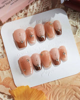 Fall Makeup nail close-up with brown gradient, tiny gems, and raised gold star details