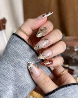 Falling leaves press-on nails with caramel nude base, gold leaf reliefs and vine linework