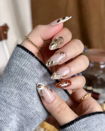 Falling leaves press-on nails with caramel nude base, gold leaf reliefs and vine linework