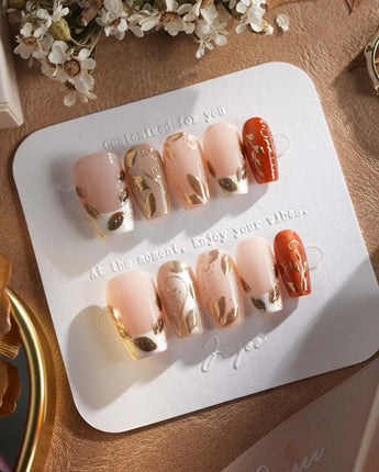 Falling leaves press-on nails with gold vine accents and caramel autumn gel design