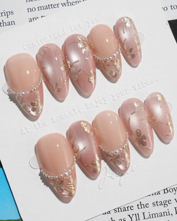 Falling Sakura-Gold nails with soft nude pink glow, gold petals, and glossy finish
