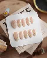 First Vow press-on nails in extra short almond shape — Gentle Milk Tea Nude, Hand-painted White Florals & Pearl Accents.