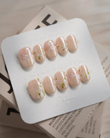 First Vow press-on nails in extra short oval shape — Gentle Milk Tea Nude, Hand-painted White Florals & Pearl Accents.