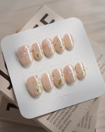 First Vow press-on nails in extra short oval shape — Gentle Milk Tea Nude, Hand-painted White Florals & Pearl Accents.