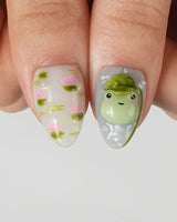 Frog Dodo watercolor-style nail set with lily pads, lotus blossoms, and 3D frogs