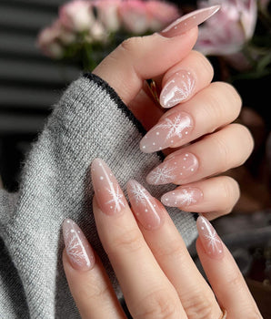 Frost Petals handmade press-on nails featuring Sheer Nude Pink, Delicate White Snowflakes.