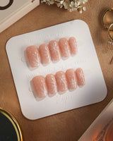Frost Petals press-on nails in short coffin shape — Sheer Nude Pink, Delicate White Snowflakes.