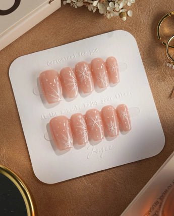 Frost Petals press-on nails in short coffin shape — Sheer Nude Pink, Delicate White Snowflakes.