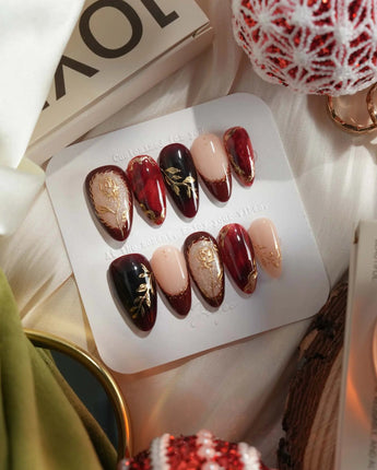 Gilded Merlot press-on nails with glossy deep red cat-eye and ornate gold floral details