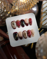 Gilded Merlot medium oval press-on nails with deep red cat-eye and gold rose reliefs