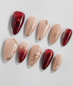 Gilded Rouge nail set with warm burgundy amber base and raised metallic gold leaf detail